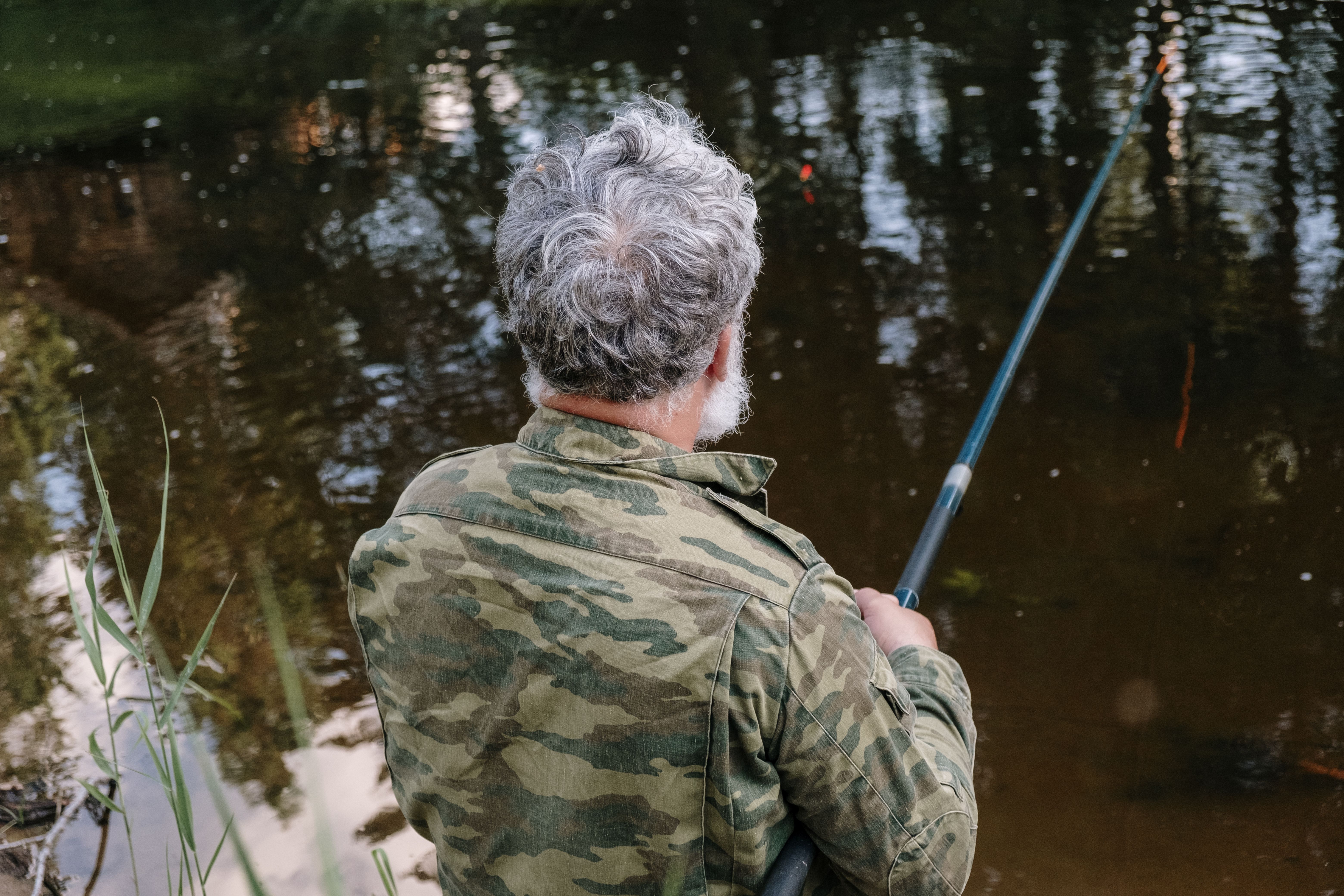 Grey-haired retiree enjoying a peaceful fishing session by the lake