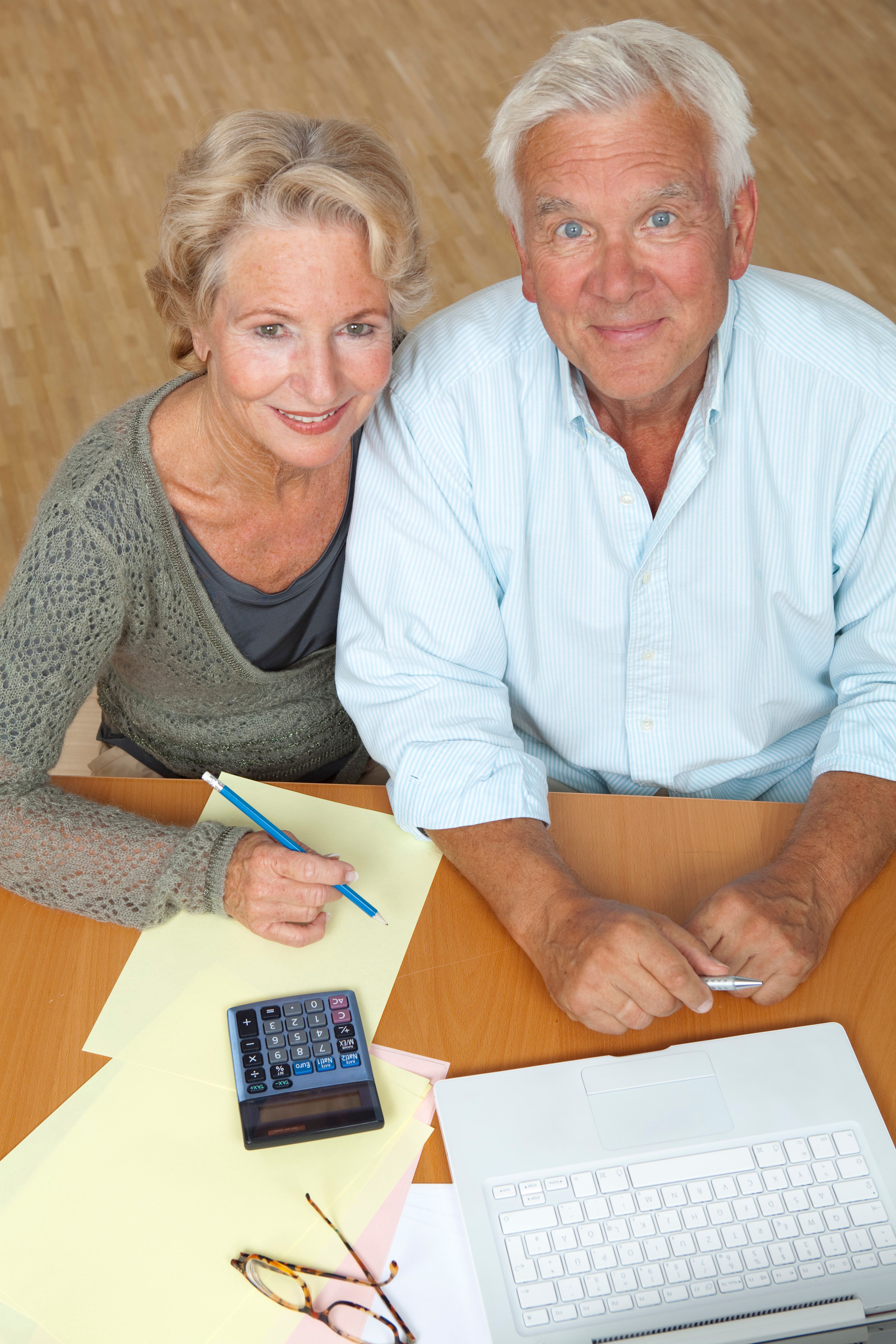 Happy senior couple using a laptop and calculator for retirement financial planning